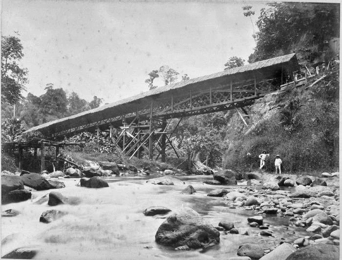 Een overdekte houten brug over een rivier.. 1898 | Indonesia - Bouwer Eerste Houten Brug Over Rijn