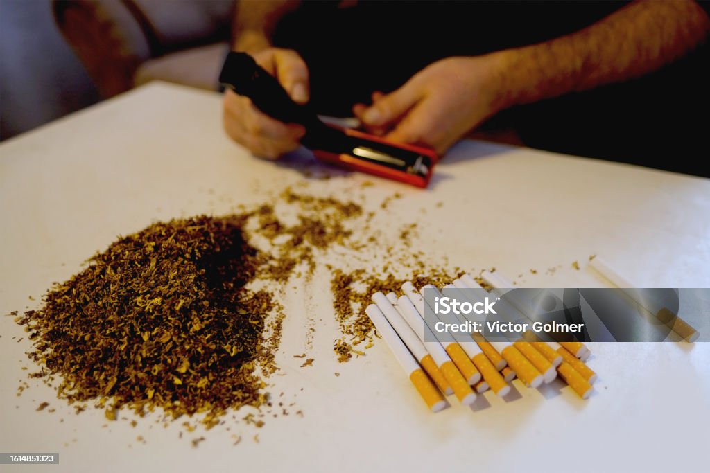 Male Hands Holding Manual Cigarette Tobacco Rolling Machine Pile Of Cut - Sigaretten Met Minste Teer En Nicotine