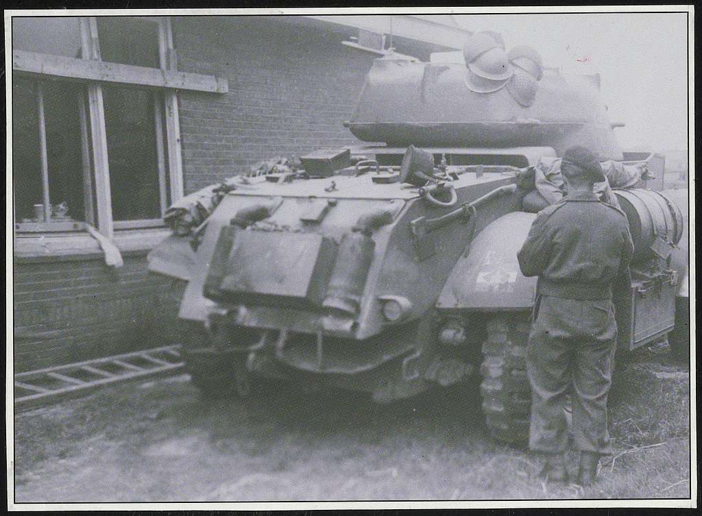 Soldaat bij een tank staand voor een huis na de bevrijding, Amerikaanse - Amerikaanse Soldaat Steekt Zich In Brand
